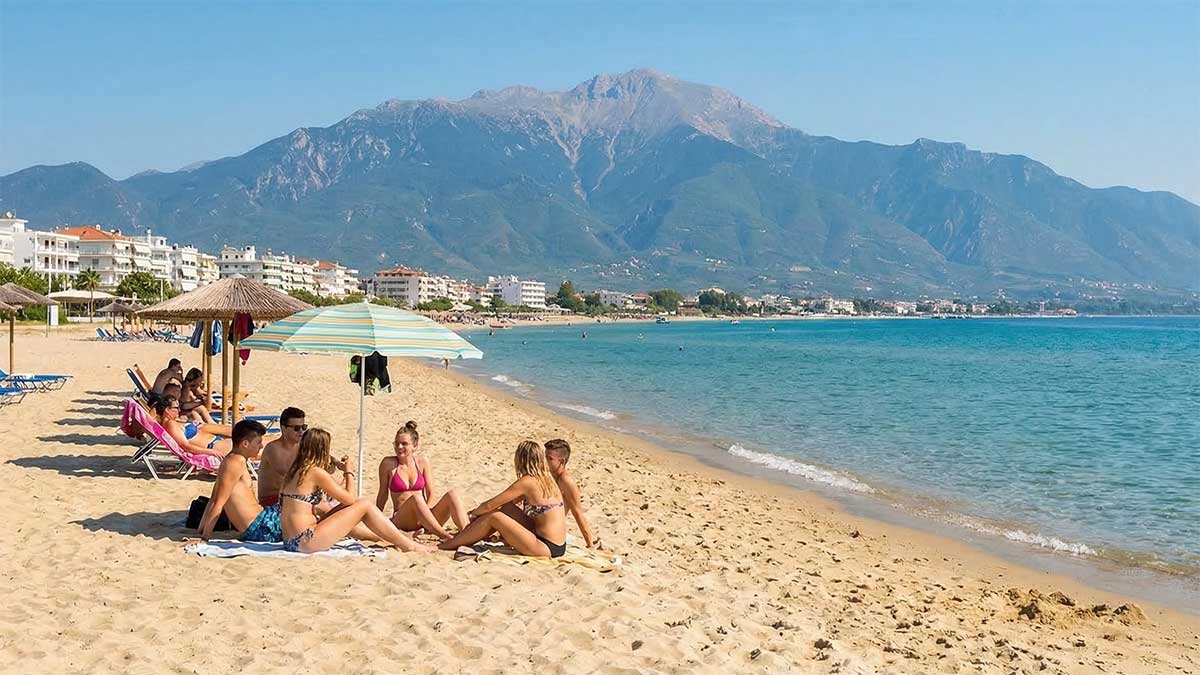 Błękitne morze, biała plaża, zarys mitycznego Olimpu w tle